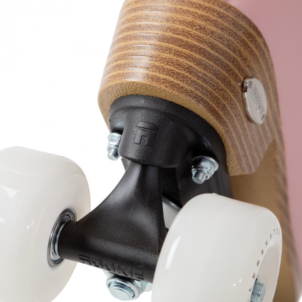 Close-up of the Rookie Classic 78 Quad Roller Skates - Pink by Rookie, featuring white wheels, a black metal truck, a brown wood-textured heel with a metal screw, and a pink body.