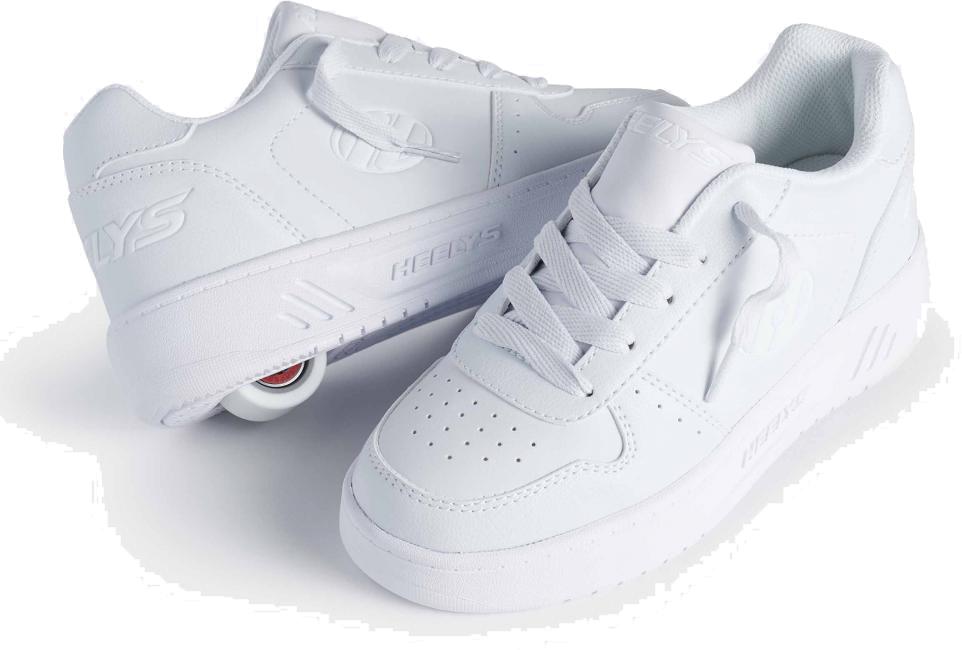 A pair of Heelys Kama Girls Shoes in white by Heelys, featuring low-profile retractable wheels—one shoe shows the wheel, the other is beside it. Both have laces and a sporty court-style look.