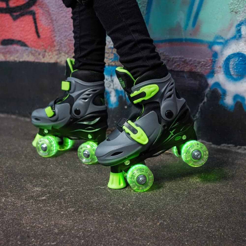 Close-up of a person wearing Xootz LED Adjustable Quad Roller Skates in green, standing on pavement by a colorful graffiti wall.