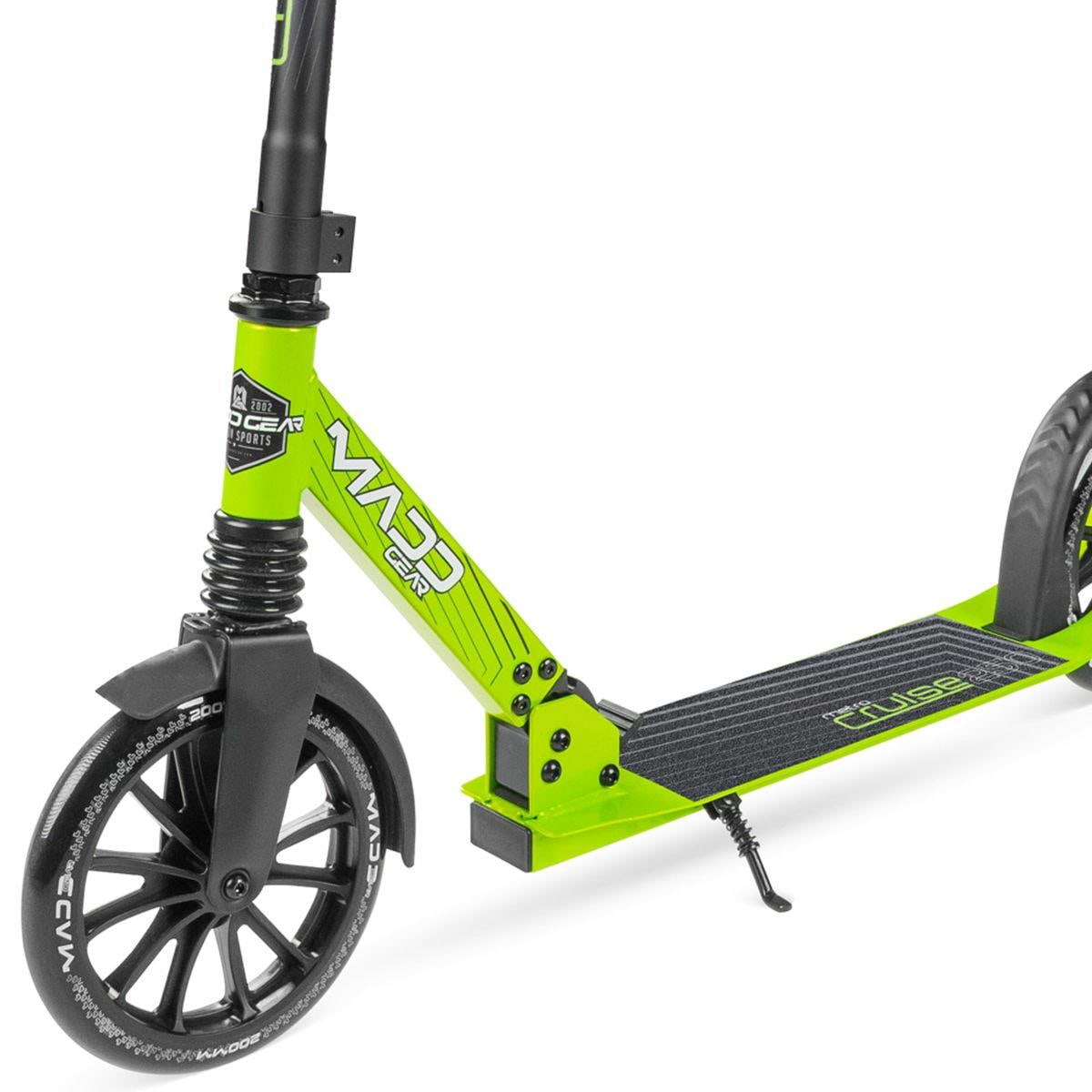 A close-up of the Madd Gear Metro Cruise 250 Foldable Commuter Scooter in Black/Lime shows its bright green frame, black wheels and handlebar, extended kickstand, "Madd Gear" branding on the frame, and textured foot deck.