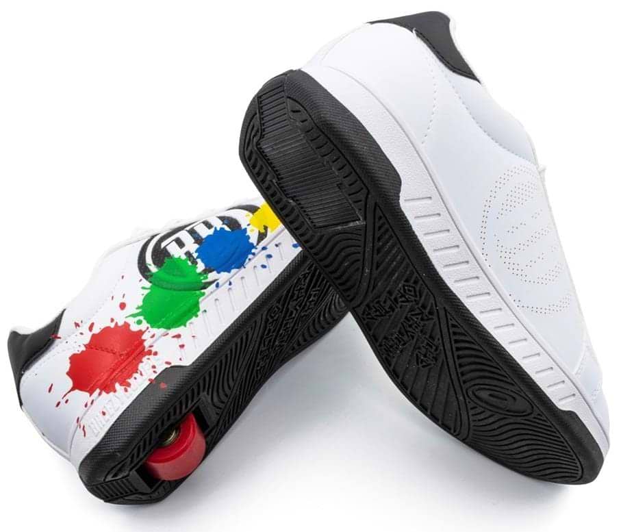 Breezy Rollers Splash Shoes in white, black, and multicolored feature a patented wheel system with visible red wheels, playful paint splatters on one shoe, and a perforated circular design on the other.