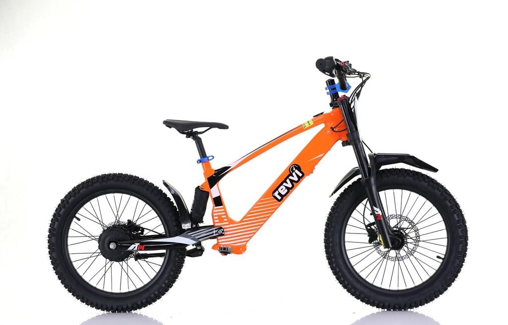 The Revvi 20" Kids Electric Balance Bike in orange features a bold frame against a white backdrop. Equipped with hydraulic disc brakes, it has black handlebars and seat, and details such as a pedal and gear system, with "Revvi" on the frame.