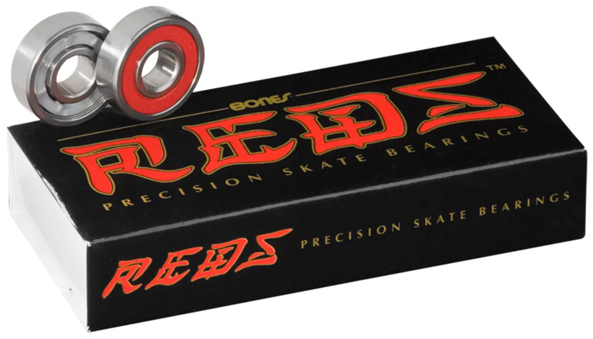 A black box labeled "Bones REDS Skateboard Bearings - 16 Pack" by Bones is topped with two metal skateboard bearings, one displaying a red inner ring.