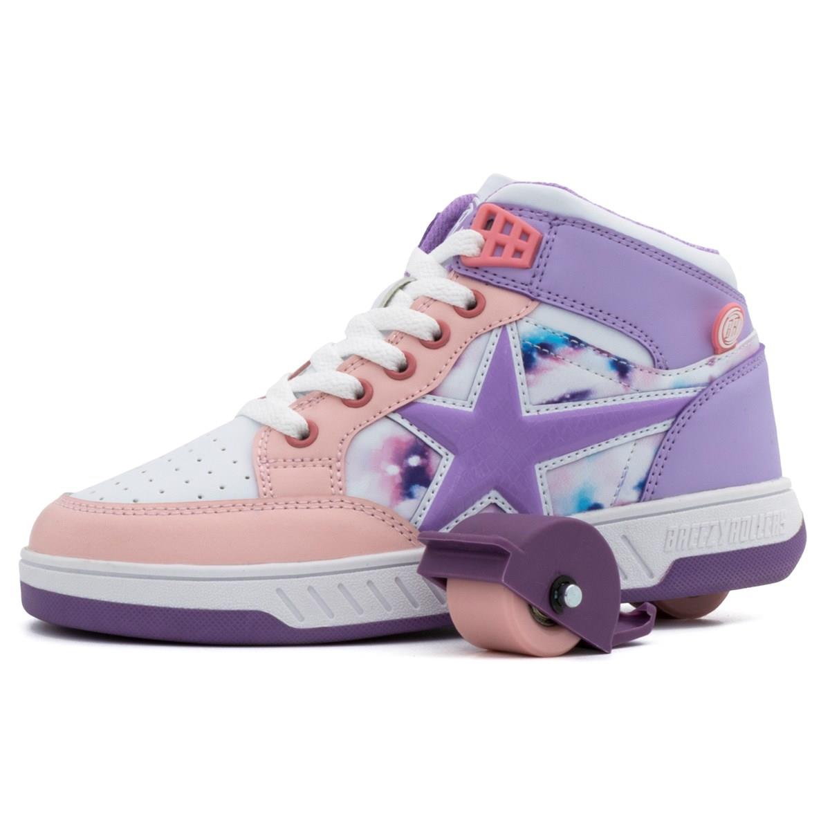 The Breezy Rollers Skater Girls Shoes in white, purple, and pink feature a star and galaxy design with a retractable pink roller skate wheel on the heel, inspired by the Breezy Rollers brand.