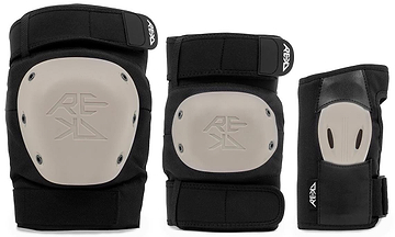 The REKD Shield Triple Skate Protection Pad Set in Black/Beige includes a knee pad and elbow pad with beige hard shells, plus a wrist guard with a high-impact palm splint—all offering premium action sports protection and featuring the REKD logo.