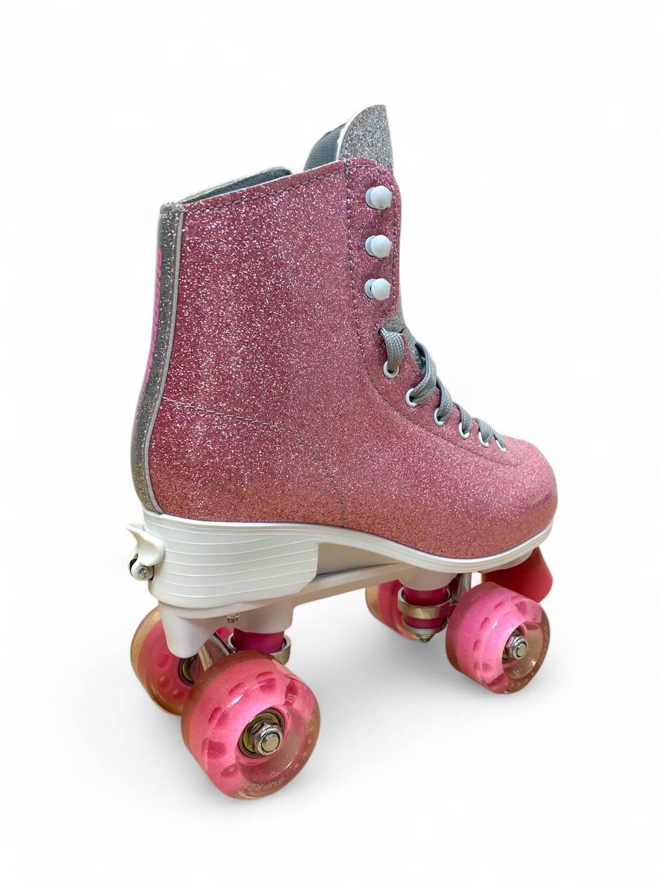 The Supreme Del Rey Adjustable Quad Roller Skates - Pink by Supreme is a kids’ roller skate featuring a pink glittery design, white laces, four pink wheels, and a white sole, displayed on a white background.