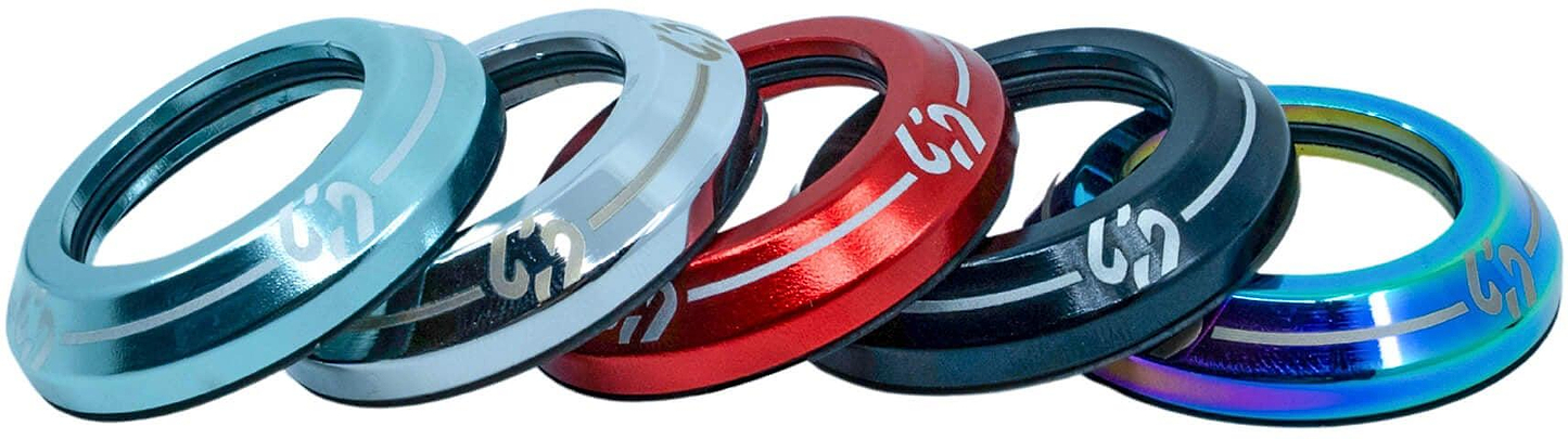 The CORE Icon Integrated Stunt Scooter Headset in red features a “CD” logo, groove design, and metallic finish. Part of the CORE range, it ensures smooth rotation and is shown lined up with other color options against a white background.