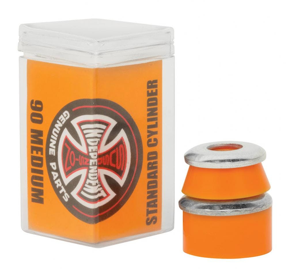 The image showcases Independent Standard Cylinder Orange Skateboard Bushings - 90A, made from high-rebound urethane, next to a transparent plastic box featuring the "Independent Genuine Parts" logo and labeled with "Standard Cylinder.