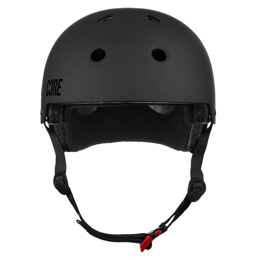 The CORE Street Skate / Scooter Helmet in Stealth Black is displayed, featuring adjustable straps and multiple ventilation holes to enhance safety for activities like biking or skateboarding. This helmet showcases sleek, minimalist aesthetics with a matte finish and includes CORE Lux Pads for added comfort.
