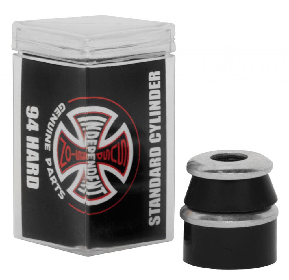 A black container featuring the Independent logo and text identifies it as containing "Independent Standard Cylinder Black Skateboard Bushings - 94A" and "Genuine Parts." Next to it are two expertly stacked black and silver cylindrical parts made with high rebound urethane Independent Standard Bushings.
