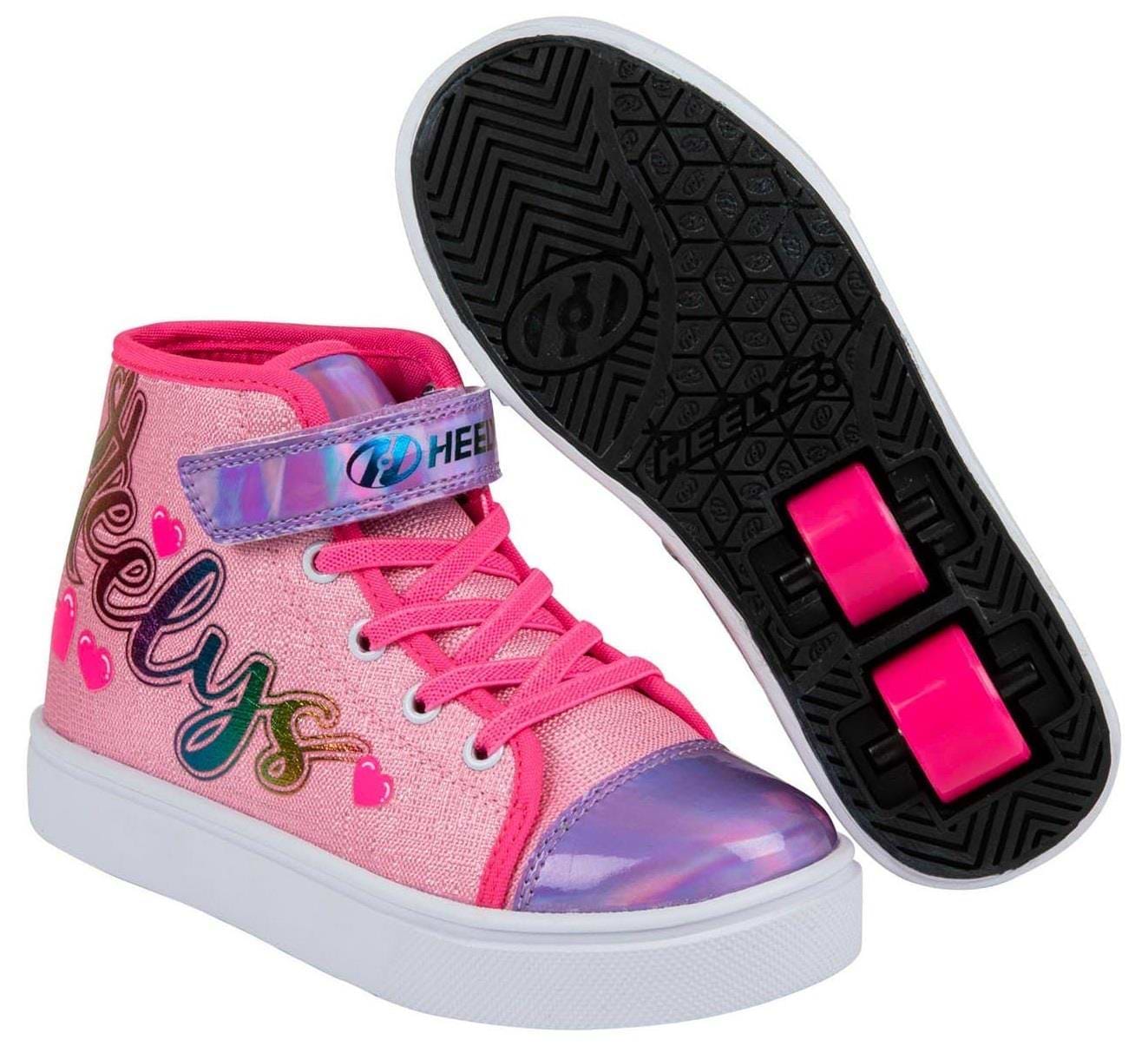 A pair of Heelys Veloz X2 Prints Girls Shoes in Prism Pink/Neon Pink/Multi with rainbow “Heelys” text, heart designs, synthetic upper, and pink low-profile wheels. One shoe is shown side-on; the other shows the wheels from below.