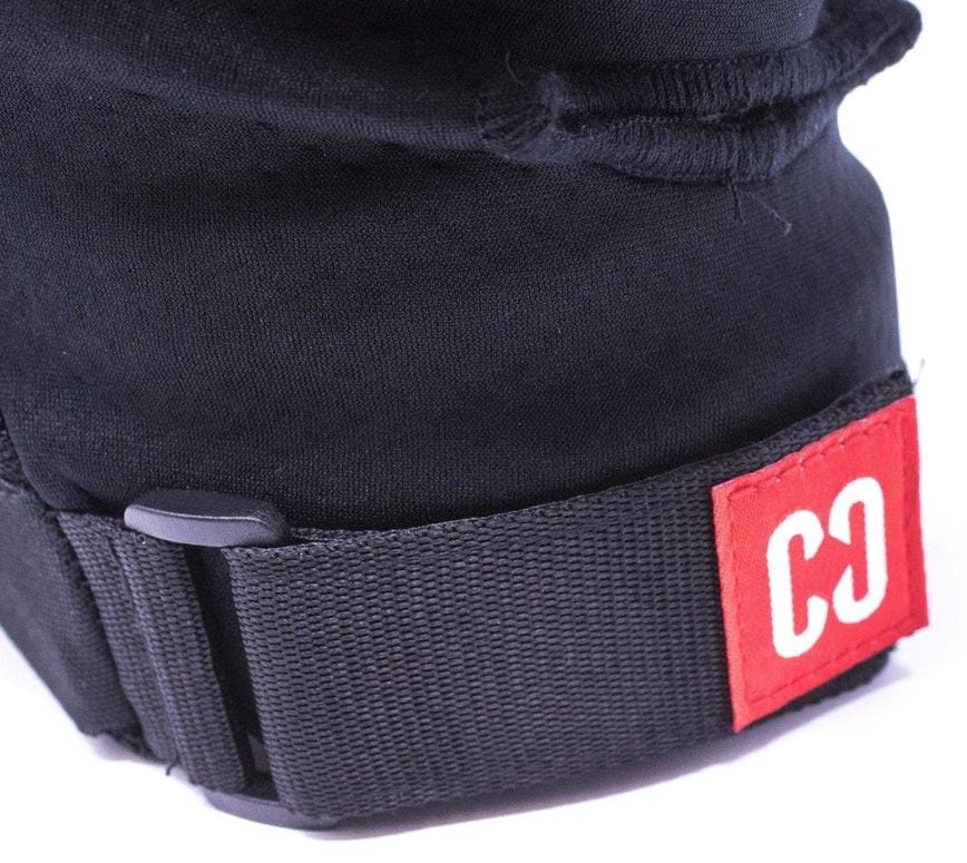Close-up of a black strap with plastic buckle from the CORE Combo Street Knee & Elbow Skate Protection Pad Set - Black by CORE, featuring a red tag with white "CC" letters sewn onto the end.
