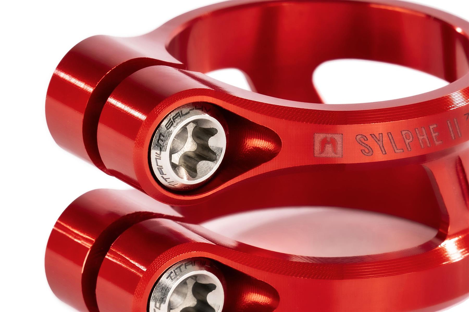 Close-up of two stacked Ethic Sylphe V2 2 Bolt Oversized Stunt Scooter Clamps in metallic red with titanium bolts and engraved "SYLPHE" text, showcasing their lightweight anodized finish and detailed machining.