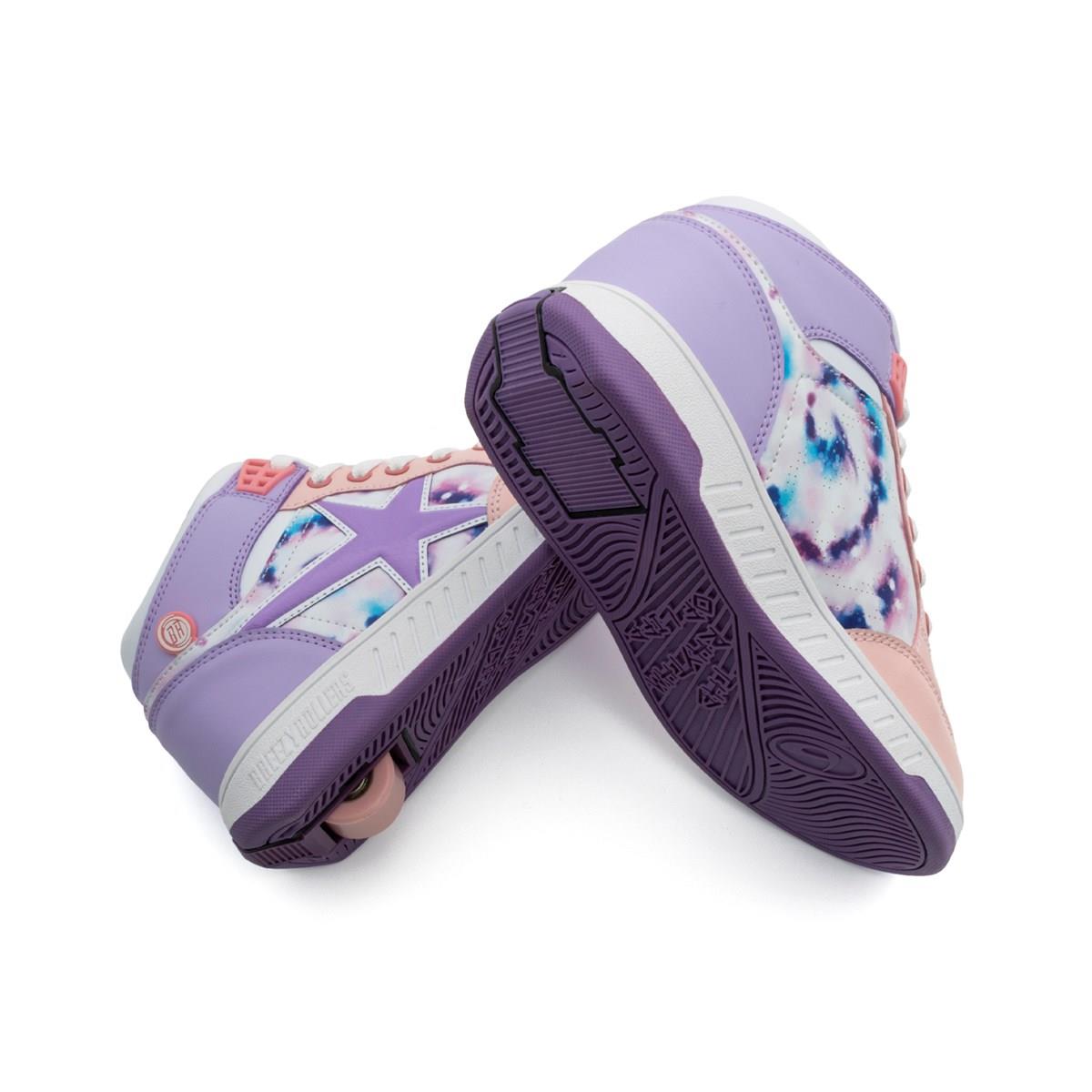A pair of Breezy Rollers Skater Girls Shoes by Breezy Rollers in white, purple, and pink with tie-dye star designs. Purple soles complete the look; one shoe shows its retractable heel wheel, while the other rests stylishly on its side.
