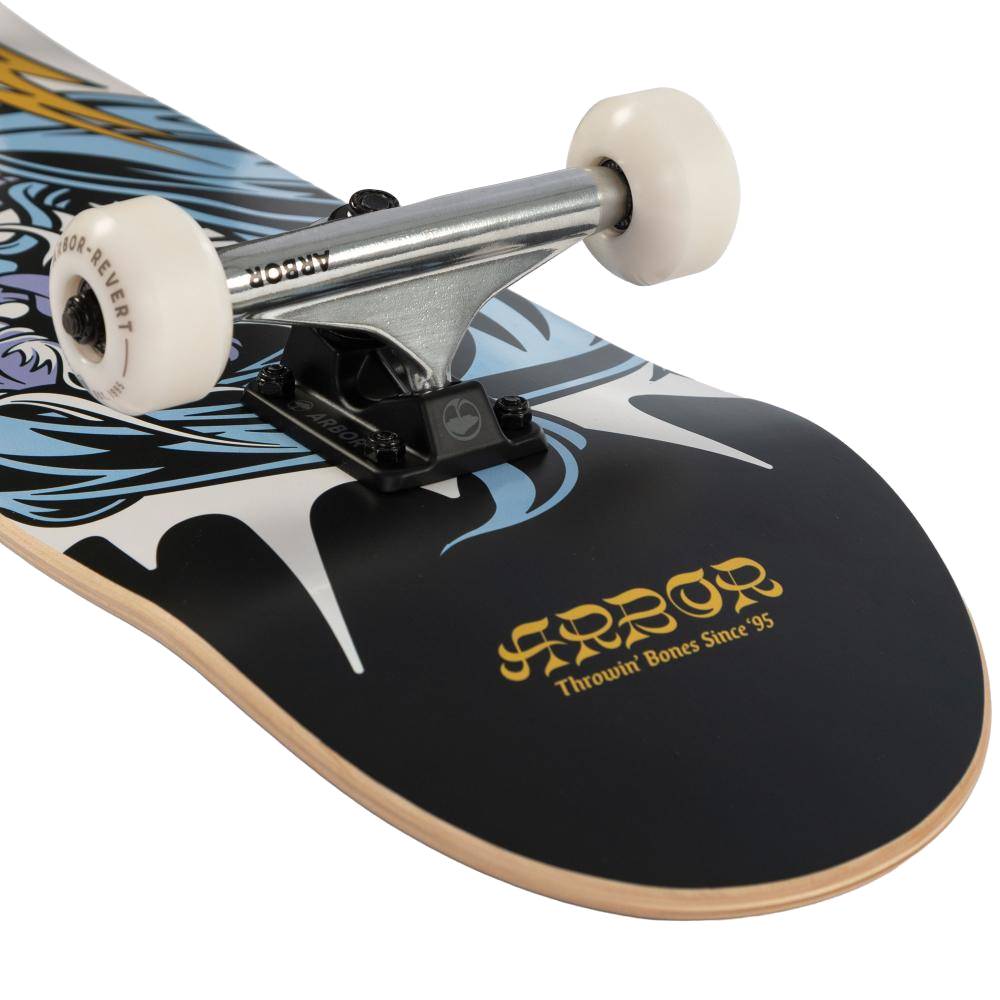 Close-up of the Arbor Street Revert Wizard Complete Skateboard - 8.25″ x 32″ with white wheels, silver trucks, a black and blue graphic deck, and “ARBOR Throwin’ Bones Since 95.” text in yellow.