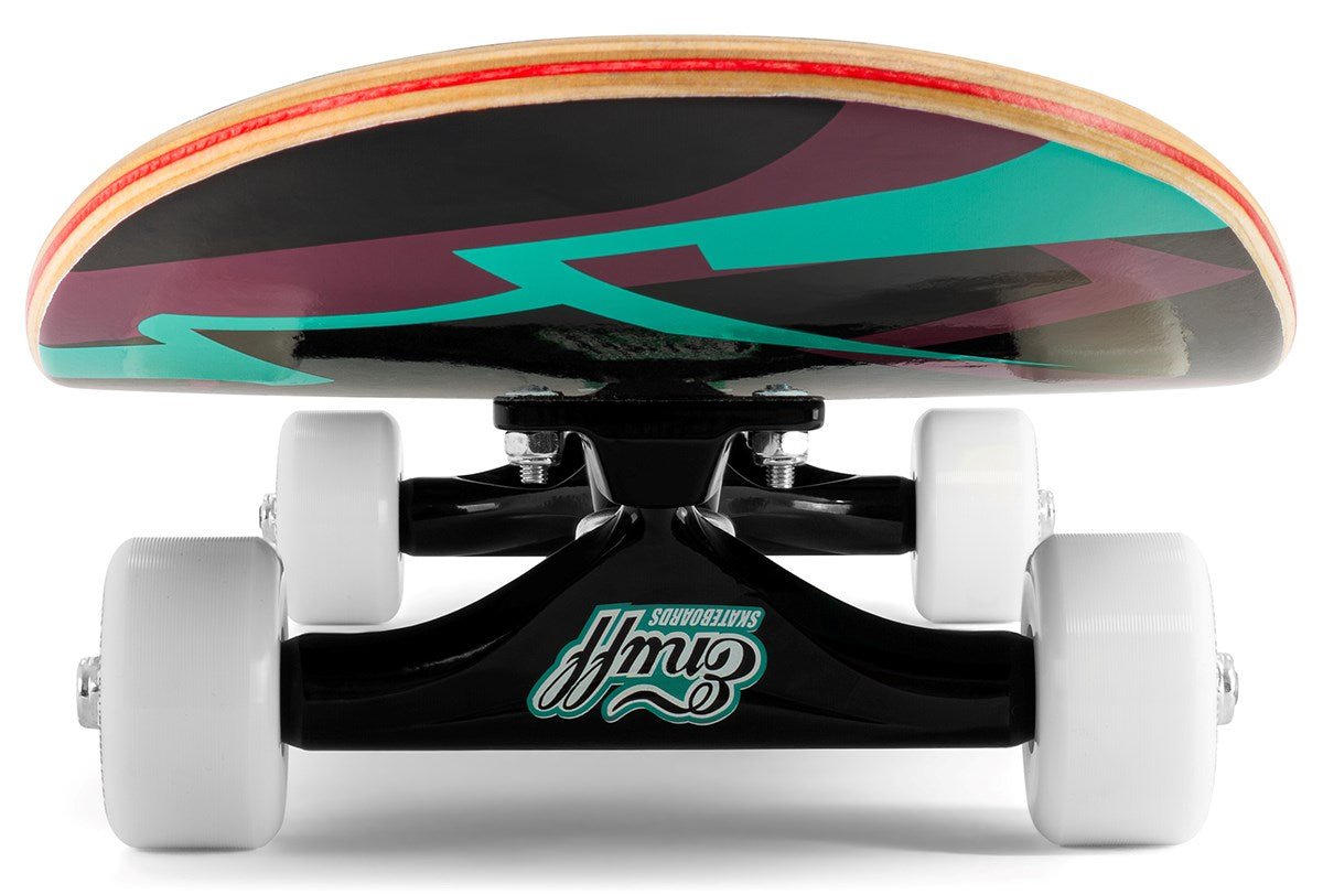A close-up, low-angle view of the Enuff Pyro III Blue Complete Skateboard (7.75" x 31.5") shows white wheels, black trucks, and a vibrant deck with teal, maroon, and black patterns on sturdy 7-ply maple construction.