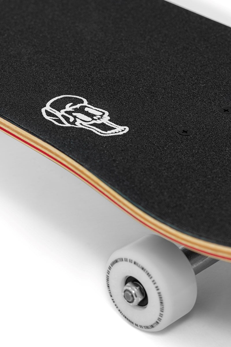 A close-up of the Enuff Throwback Black Complete Skateboard (8.5" x 32.1") shows black grip tape with a white skull graphic near the nose and a white wheel underneath.
