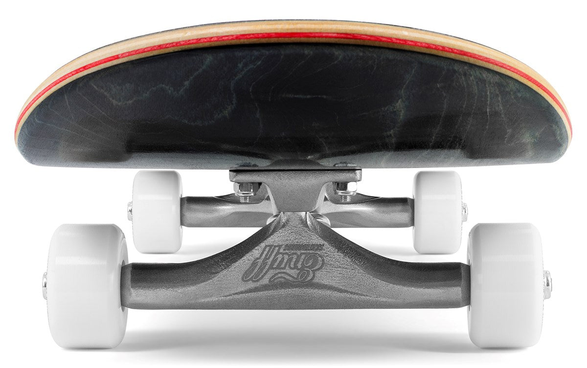 Ground-level close-up of the Enuff Throwback Black Complete Skateboard (8.5" x 32.1") showing white wheels, silver Enuff trucks with logo, and the black deck's underside with a red edge.