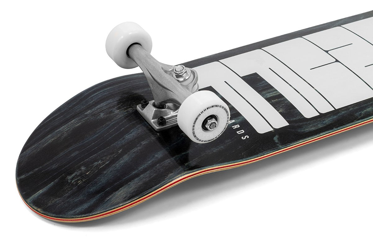 A close-up of the Enuff Throwback Black Complete Skateboard (8.5" x 32.1") shows part of its black 7-ply maple deck with a white graphic, metal truck, and white wheels, set against a white background.