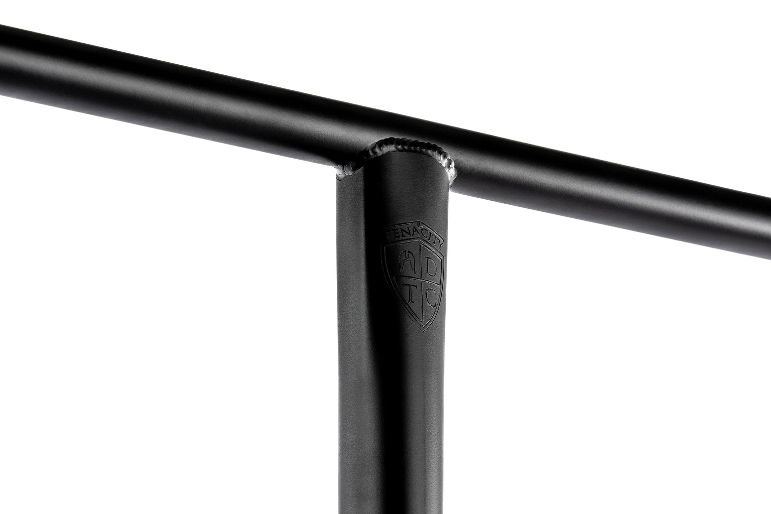 Close-up of a black Ethic DTC Tenacity V2 Oversized HIC Stunt Scooter T-Bar (770mm x 600mm) in durable 4130 chromoly steel, showing weld marks and an embossed ADTC shield logo on the upright bar, against a white background.
