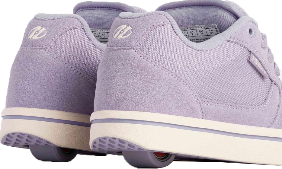 A pair of Heelys Pro 25 Girls Shoes - Purple / Cream by Heelys, shown from the back to highlight the fabric texture, logo, and size label inside.