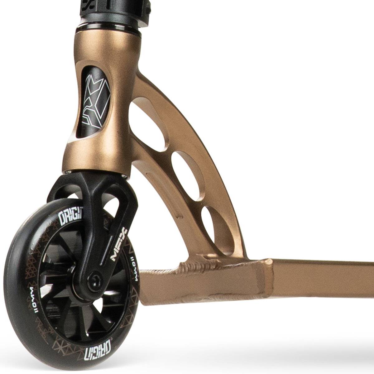 Close-up of the front wheel and deck of the Madd Gear (MGP) VX Origin IV 550 Complete Stunt Scooter in Antique Brass, showing the fork, black wheel with white graphics, and a cutout design in the metal frame.