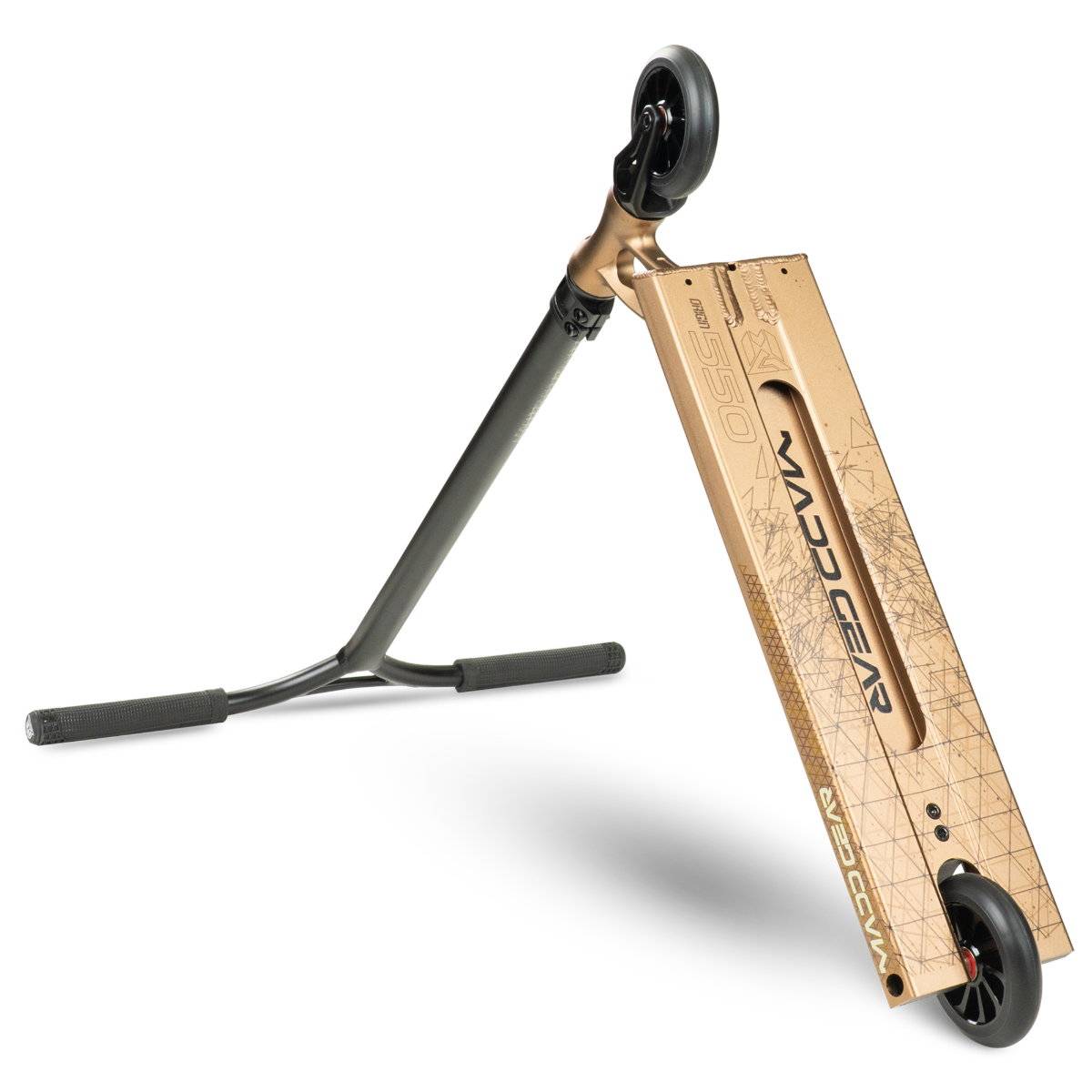 The MGP VX Origin IV 550 Complete Stunt Scooter in antique brass by Madd Gear is shown tilted on its side, featuring "Madd Gear" branding on the brass deck and black handlebars—ideal for park scooter tricks.