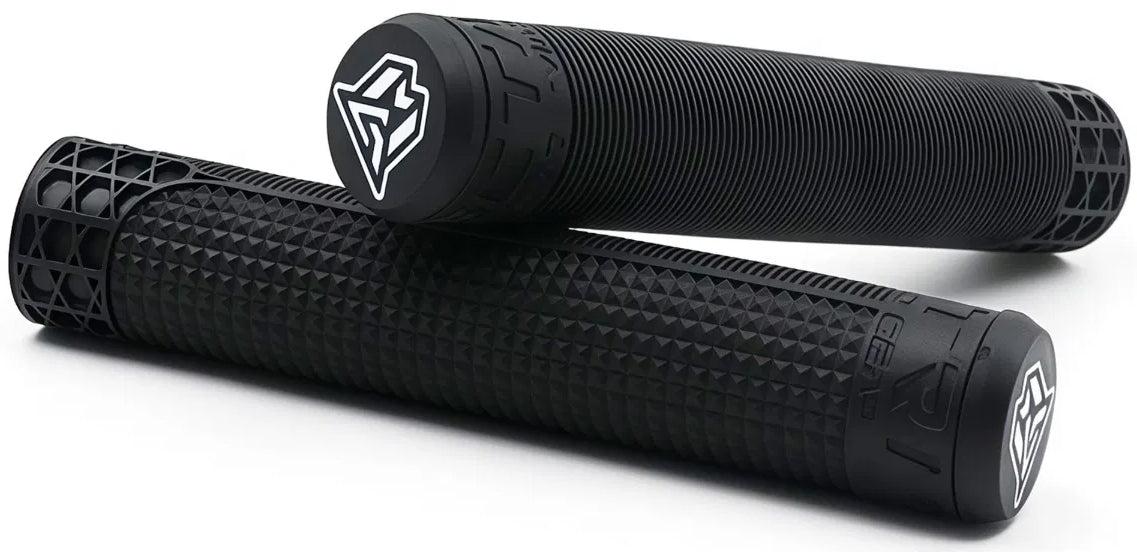 A pair of Madd Gear (MGP) MGP Trifecta Black Stunt Scooter Grips—each measuring 180mm, featuring a textured black TPR surface and distinctive white geometric logos on the end caps. One grip is positioned horizontally while the other rests angled on top, making them perfect as comfortable handlebar grips for your MGP Trifecta Stunt Scooter.
