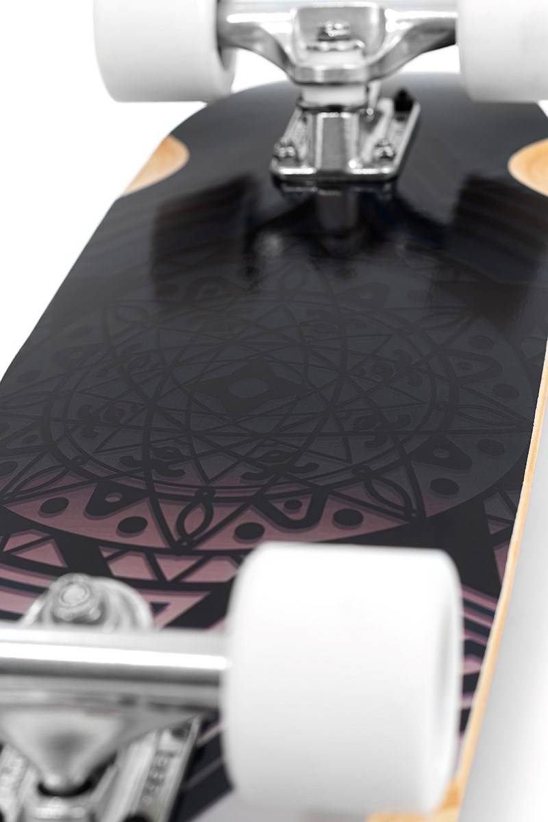 Close-up of the Mindless Drifter Cruiser Skateboard 28″ x 8″ - Black, featuring white wheels and trucks, with a black deck adorned in purple and pink geometric and circular patterns.
