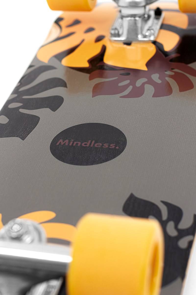 Close-up of the Mindless Oasis Cruiser Skateboard 32″ x 9″ - Black featuring yellow wheels, a black maple deck, orange and black floral patterns, and “Mindless” in the center.