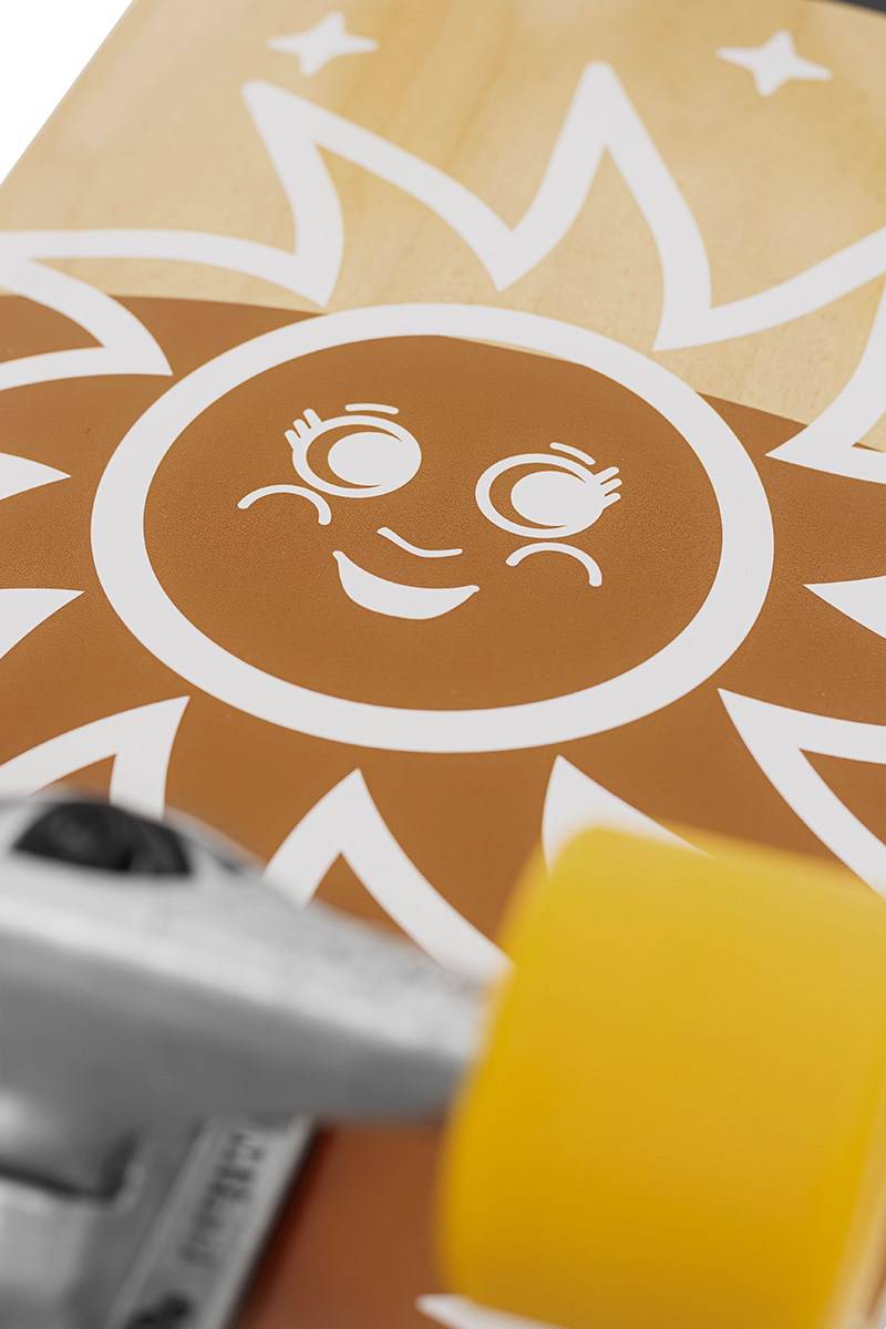 Close-up of the Mindless Soul Surf Skate Cruiser Skateboard 29.5″ x 9.75″ - Brown featuring a smiling sun graphic, yellow wheel, and surf trucks, perfect for carving.