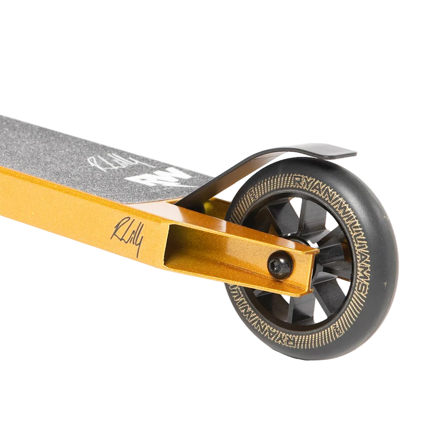 Close-up of the rear wheel and deck on the Nitro Circus Ryan Williams Junior Replica 2025 Complete Stunt Scooter in gold/black, showing black grip tape with white logos, a black brake, and a detailed patterned wheel against a white background.