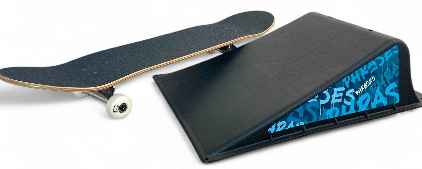 The Phrases One Way Kicker Skate Ramp by Phrases is shown with a skateboard beside it, featuring graffiti-style artwork on a white background—ideal for beginner skateboarders.