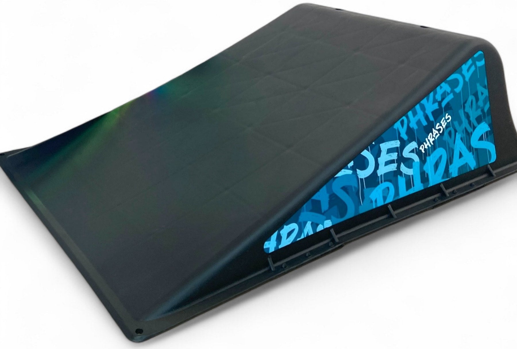 The Phrases One Way Kicker Skate Ramp by Phrases is a black portable ramp with a blue side panel featuring white graffiti text. Its smooth, angled surface is perfect for tricks and ideal for beginner skateboarders.