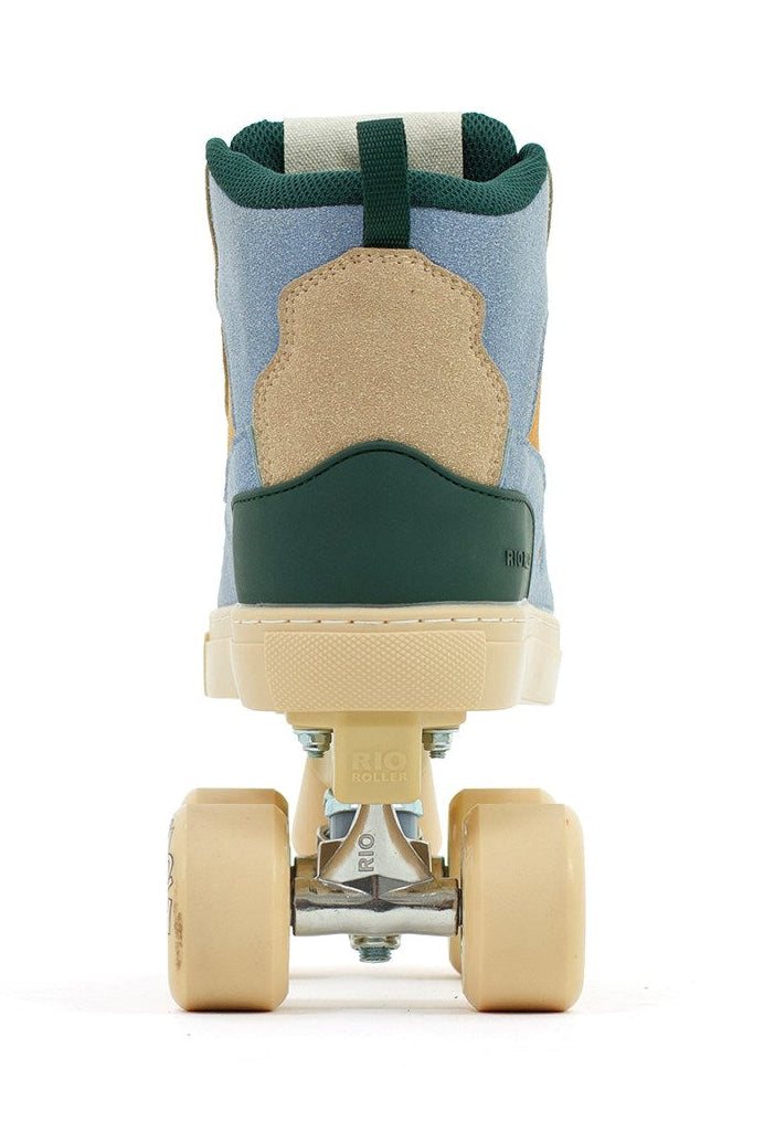 The Rio Roller Beats Quad Roller Skates by Rio Roller feature a retro design with a tan suede heel, blue upper, green accents, beige sole, and cream wheels—vegan-friendly and shown from the back against a white background.