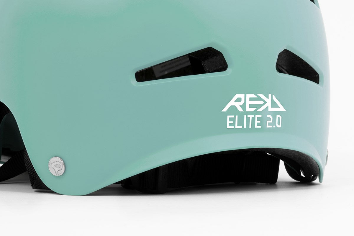 Close-up of the REKD Elite 2.0 Skate / Scooter Helmet in matt teal, a lightweight action sports helmet with two black ventilation slits and "REKD ELITE 2.0" printed in white on the back.