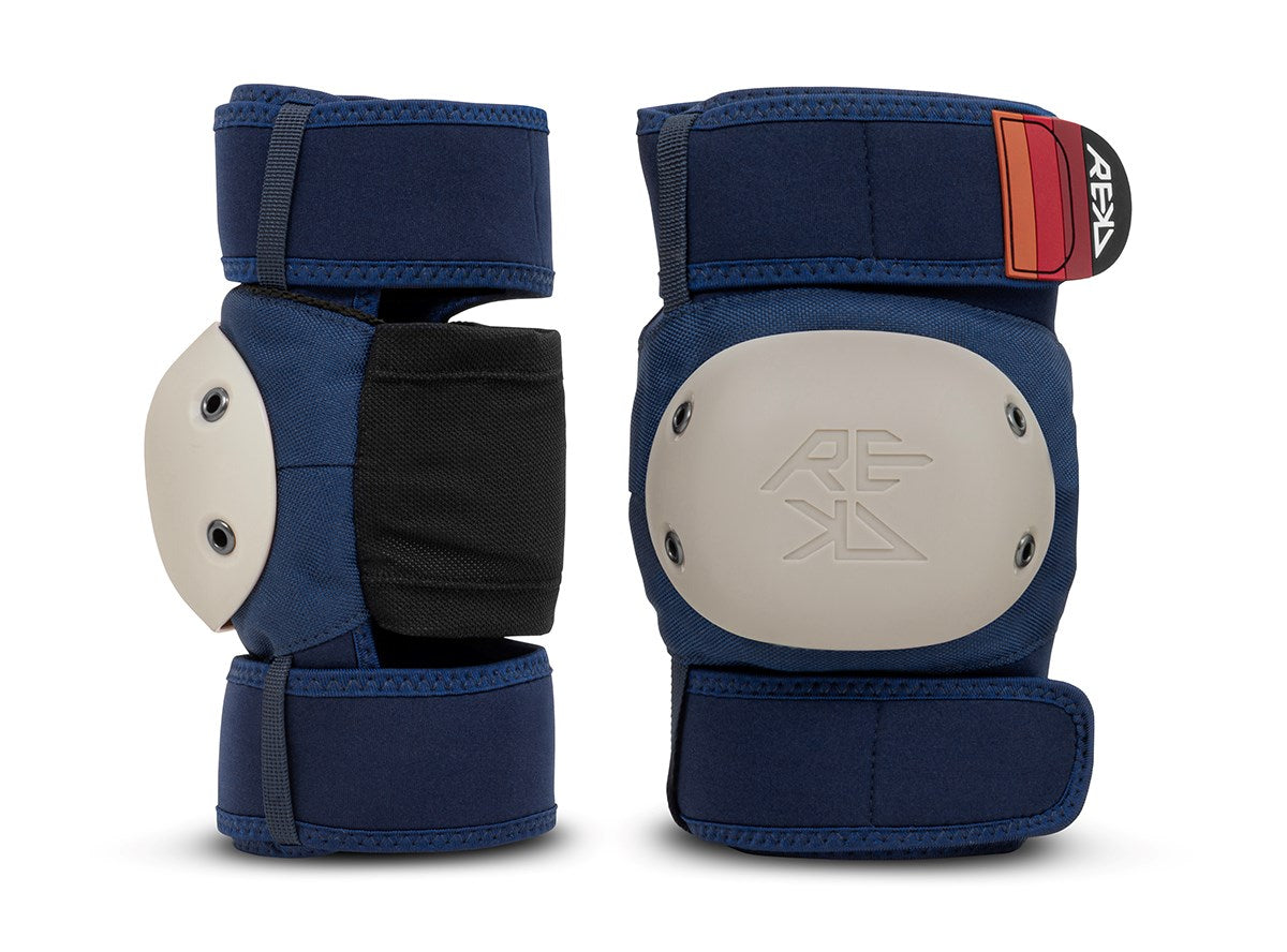 Two navy blue knee pads with beige protective caps and black padding, positioned upright on a white background, are included in the REKD Shield Triple Skate Protection Pad Set - Blue by REKD, designed for comprehensive action sport protection.