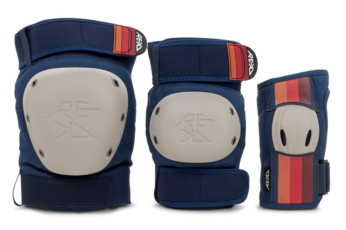 The REKD Shield Triple Skate Protection Pad Set - Blue by REKD includes three blue protective pads—a knee pad, an elbow pad, and wrist guards—each with a hard beige shell and red-striped blue straps, displayed upright on a white background.