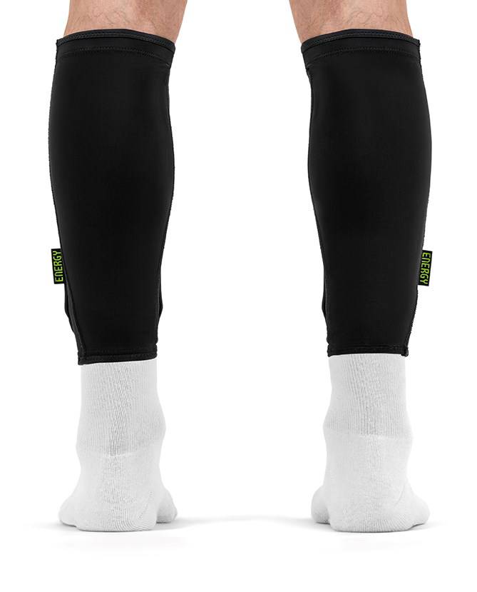 Black slim REKD Energy Covert Long Shin Skate Protection Guards worn over white socks on a person’s lower legs for protection.