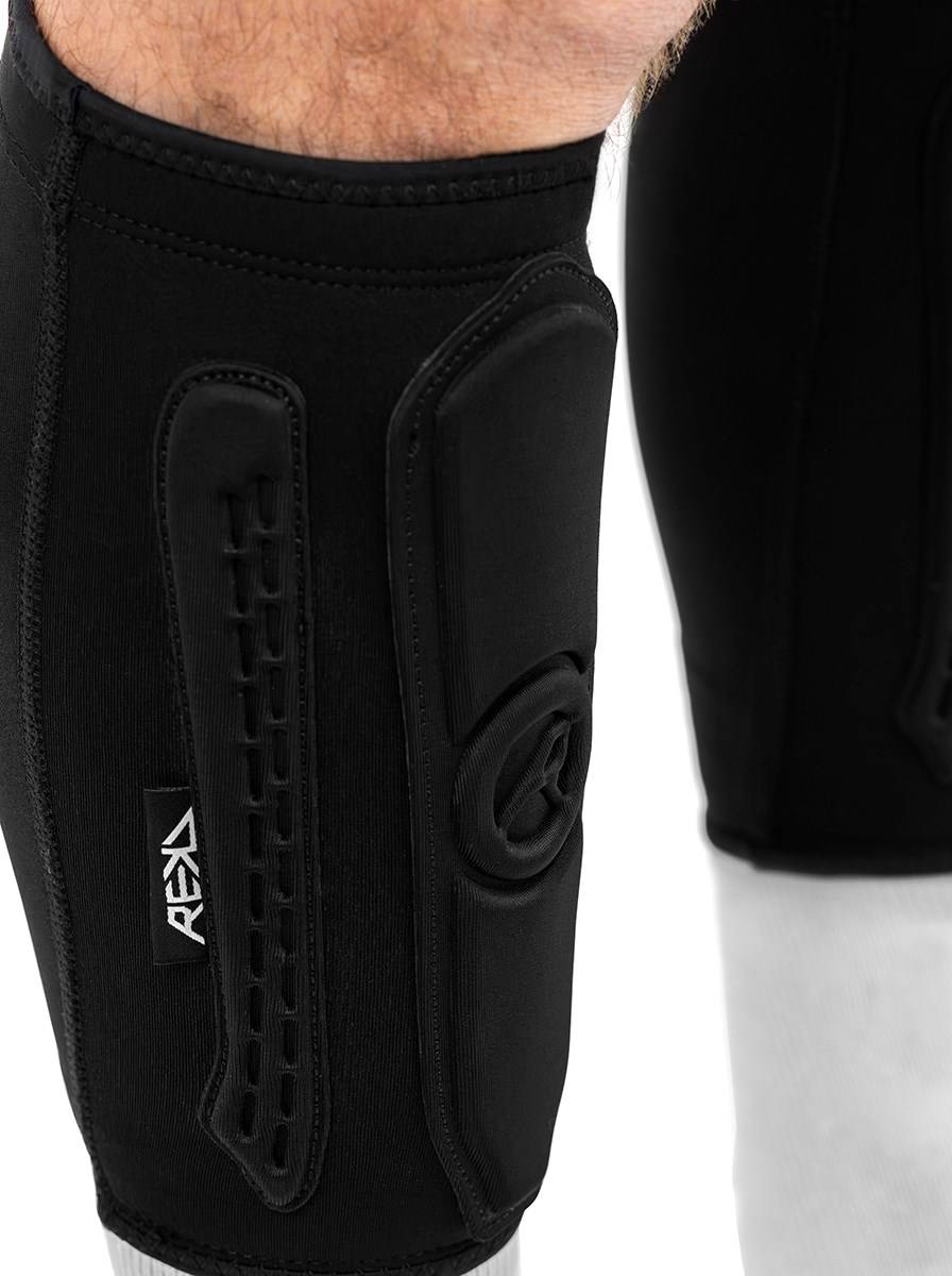 REKD Energy Covert Short Shin Skate Protection Guards in black worn on a lower leg, featuring a molded impact pad and a logo tab for slim shin protection.