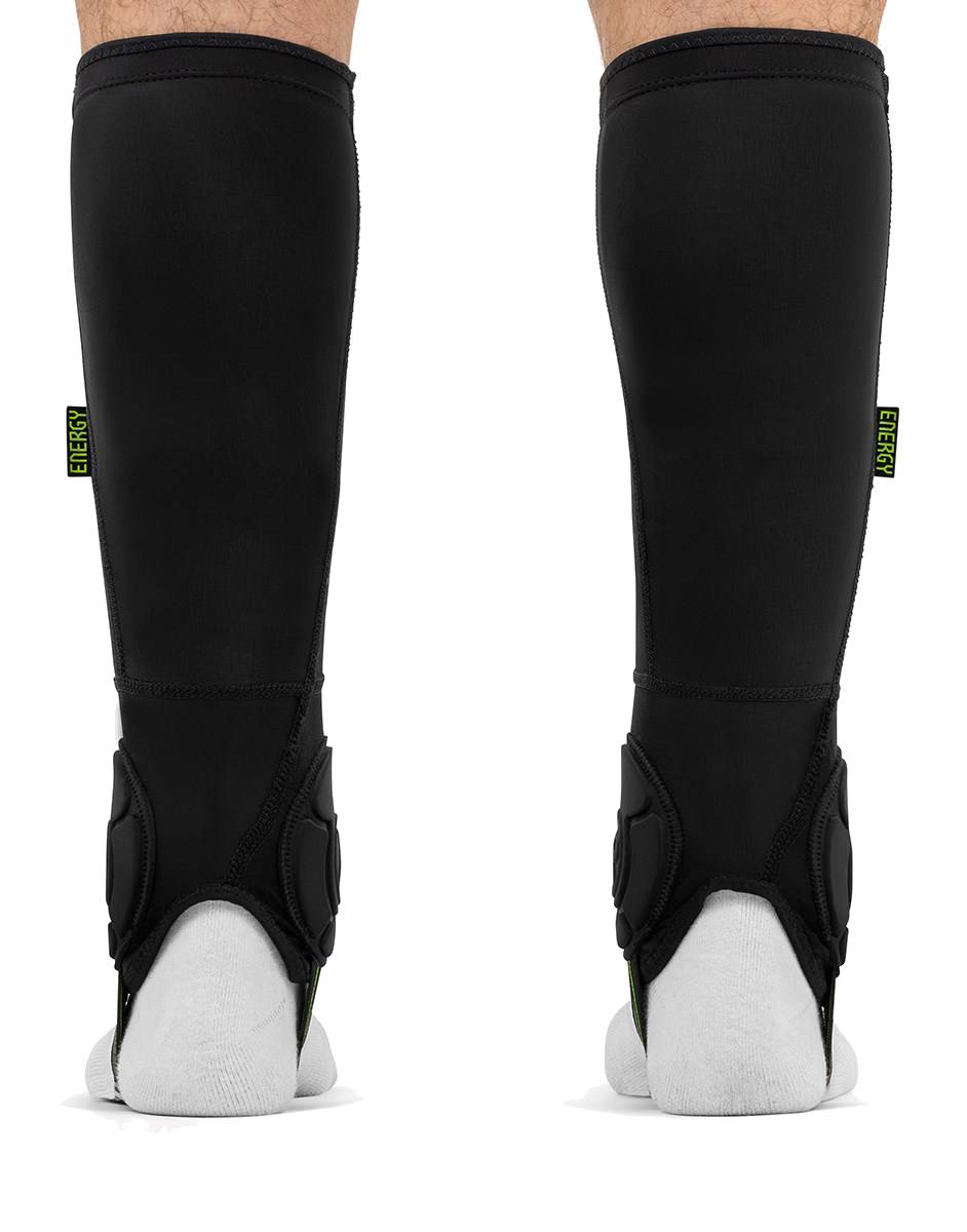 Pair of black REKD Energy Covert Short Shin and Ankle Skate Protection Guards worn on the lower legs, each featuring a small vertical label that reads “ENERGY.”