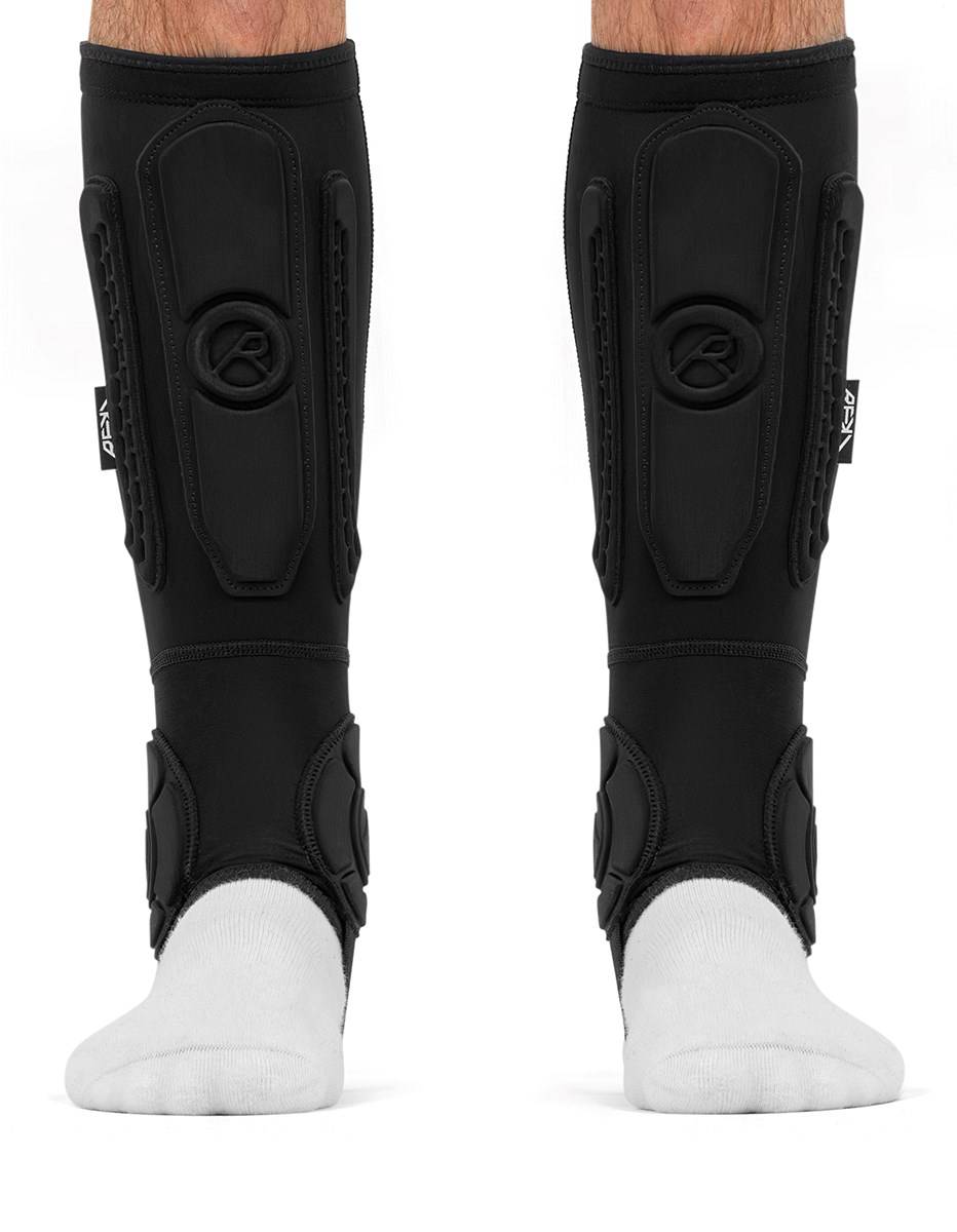 Black REKD Energy Covert Short Shin and Ankle Skate Protection Guards worn over white socks.