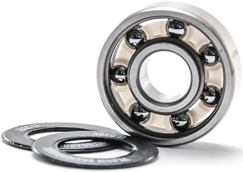 A Venom ABEC 11 Skateboard Bearings standing upright next to two thin black washers.