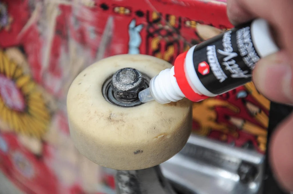 A person applying Venom AntiVenom Bearing Lube 10ml Bottle into a skateboard wheel bearing.