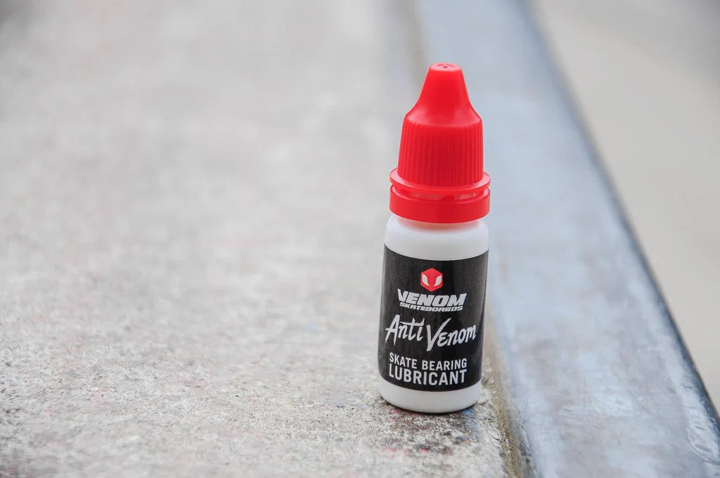 A small 10ml bottle of Venom AntiVenom Bearing Lube with a red twist-off cap, standing on a concrete ledge.