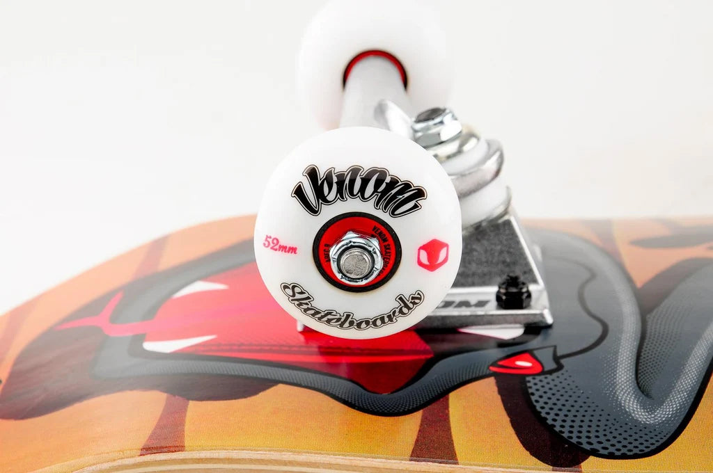 Close-up of a Venom Junior Desert Viper Kids Complete Skateboard - 7.25″ x 29″ deck featuring a graphic of a snake’s open mouth, showing a white wheel with black lettering and silver hardware.