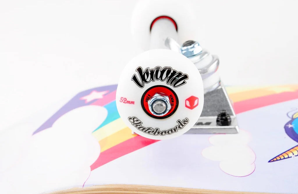 Close-up of a white wheel with a red center bearing on a Venom Junior Unicorn Kids Complete Skateboard - 7.25″ x 29″, showing a graphic of a rainbow and unicorn on the deck below.