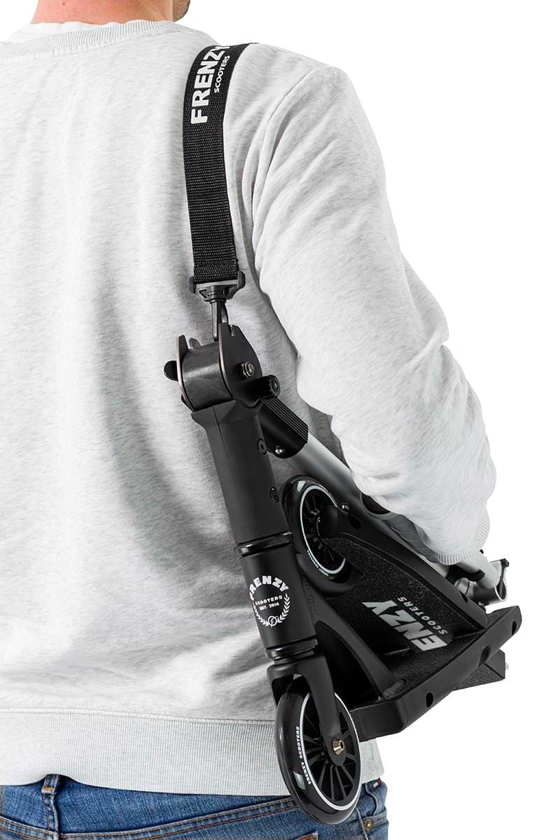 A person in a light gray sweatshirt carries the Frenzy Flex 120mm Recreational Scooter - Black / Silver over their shoulder with a "FRENZY" strap. Its patented folding design keeps the wheels and deck visible for easy, compact storage.