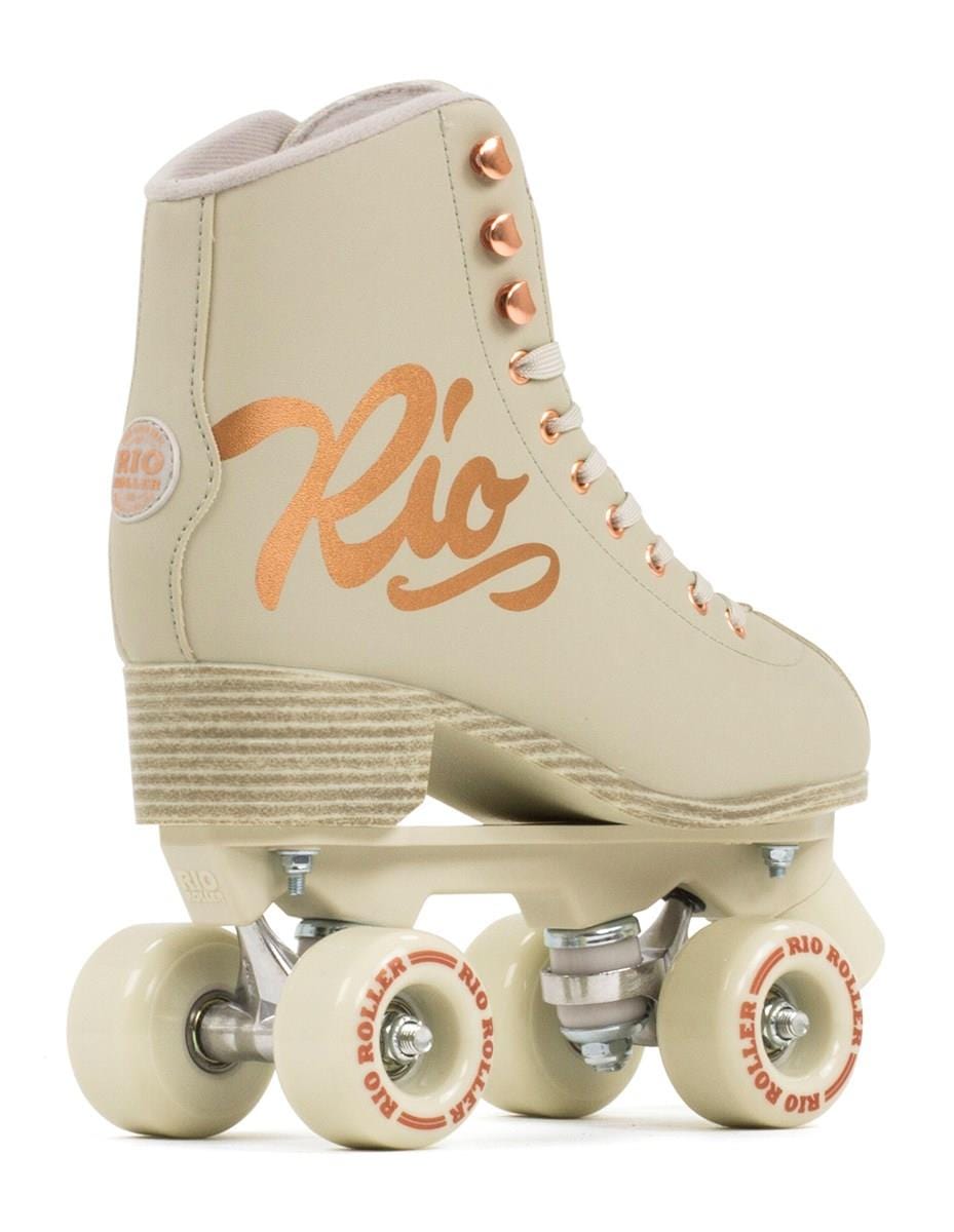 The Rio Roller Rose Quad Roller Skates - Rose Cream from Rio Roller feature a beige design with rose gold accents and a leather-like finish. The side is adorned with the elegant "Rio" script, while the cream-colored wheels and stopper prominently showcase the "Rio Roller" branding.
