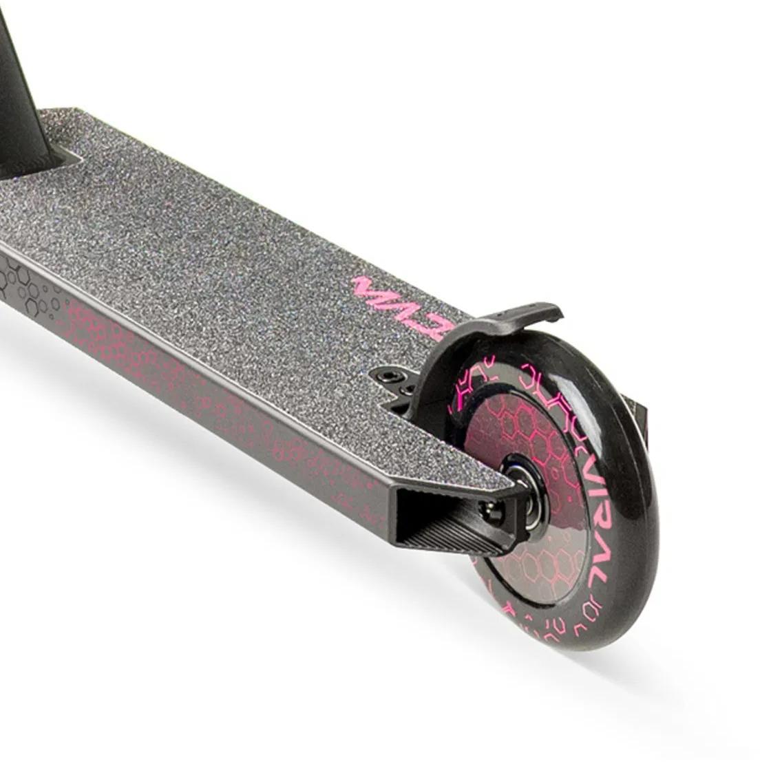 Close-up of the Madd Gear Viral Rave Complete Stunt Scooter - Melon shows its textured deck with a pink hexagon pattern and branding, plus a single black wheel featuring a pink honeycomb design.